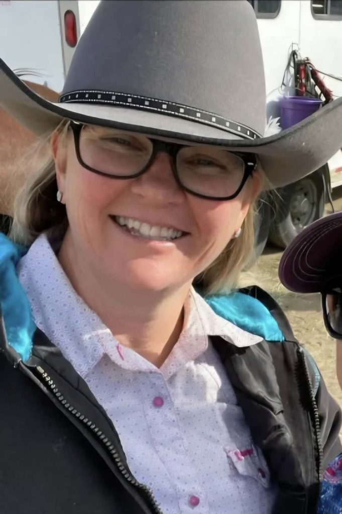 A woman with a cowboy hat smiles at the camera.